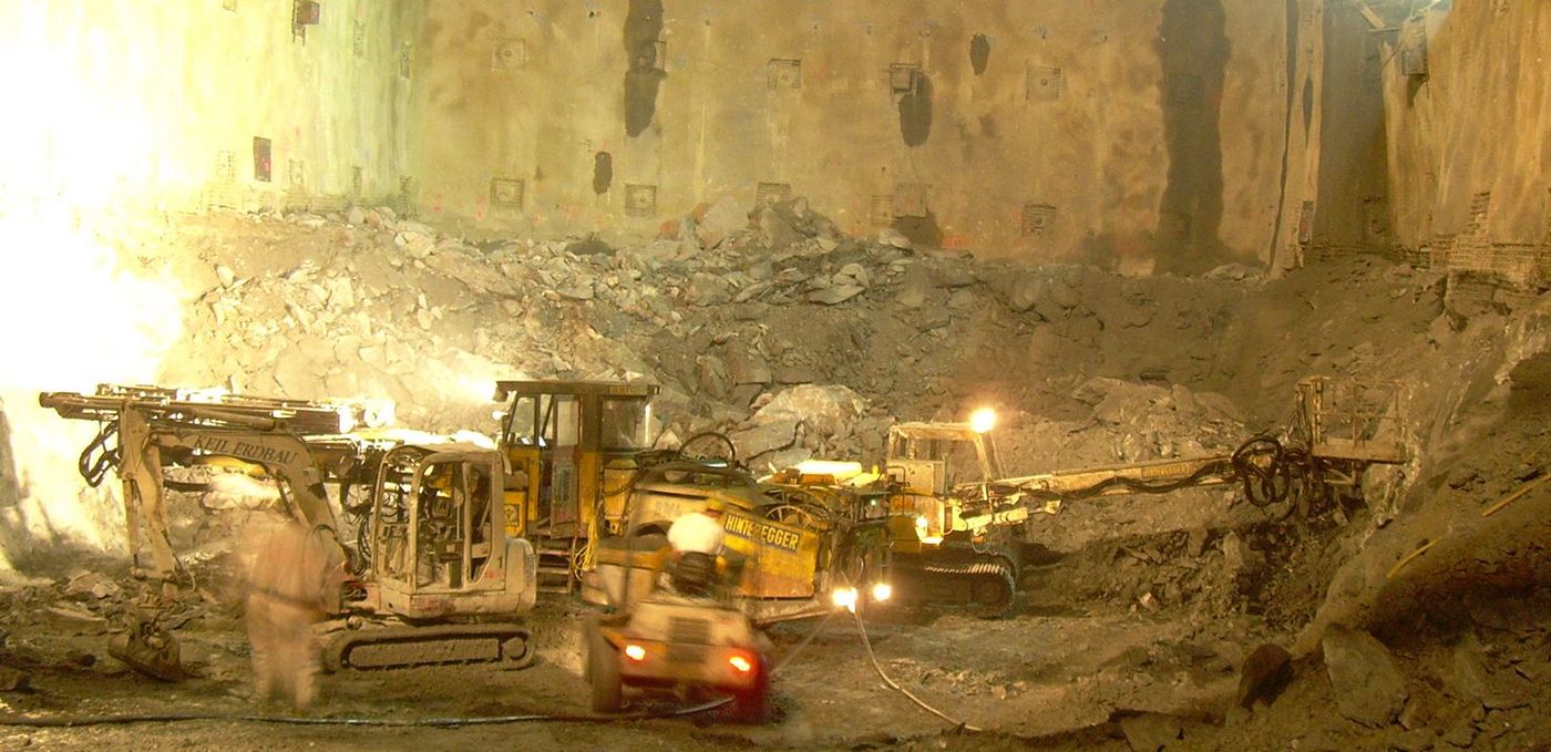 Foto: Baumaschinen bei Ausbruchsarbeiten in einer großen, sehr hohen Felskaverne